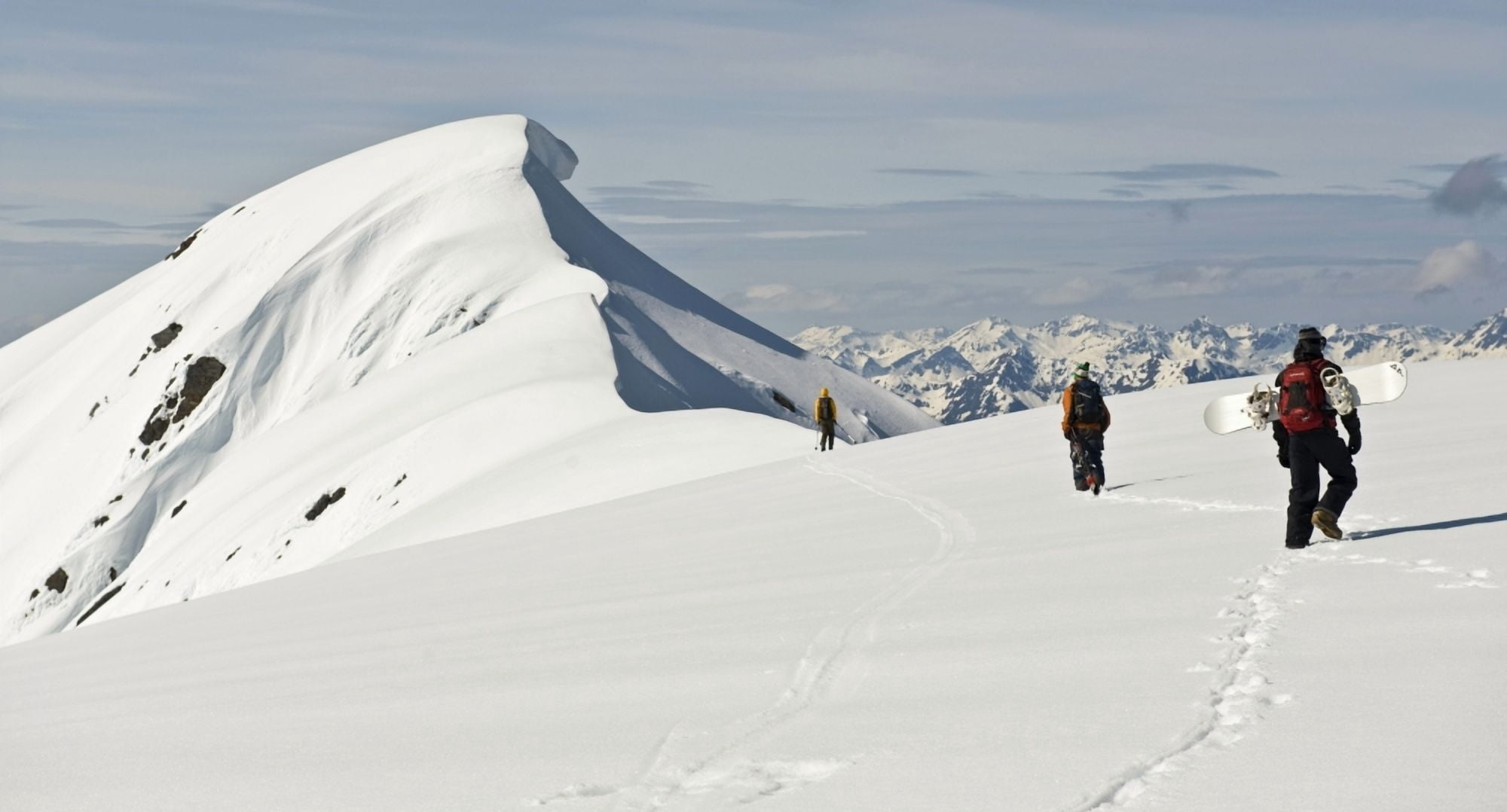 A Corniced Mt Hawthorne Rises In The Background As Skiers And A Snowboarder Hike To Get A Better View Of The Summit While Heli-Skiing Near Juneau Alaska Canvas Art - Chris Miller Design Pics (42 x 22