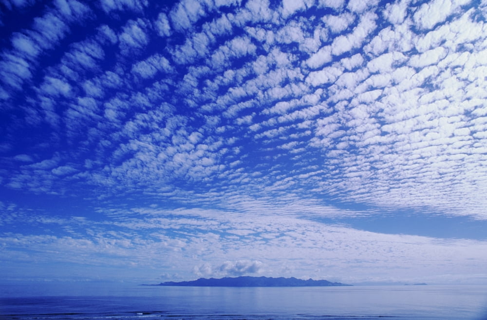 Cotton-Like Clouds In Blue Sky Over Smooth Ocean Water Island In Distance Canvas Art - Larry Dale Gordon  Design Pics (34 x 22)