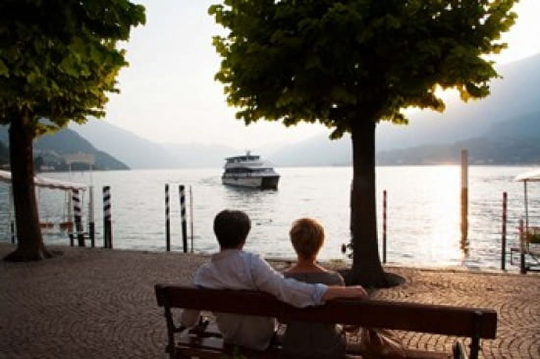 Couple sitting on bench and watching ferry approaching dock along the Lake Como Bellagio Province of Como Lombardy Italy Canvas Art - Panoramic Images (36 x 24)