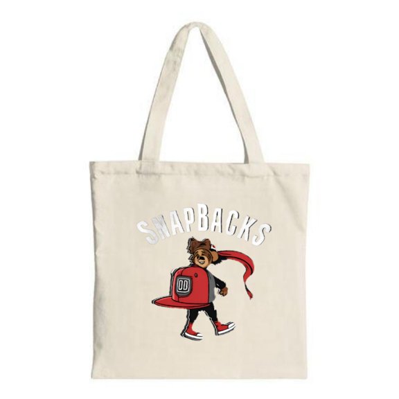 Cream Canvas Tote Bag featuring a cartoon bear in a red cap holding a ribbon with ' SNAPBACKS ' in bold white letters above