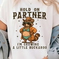 thumbnail image 1 of DOPASHIRT Hold On Partner I'M Growing A Little Buckaroo Shirt, Cowboy Baby, Country Mama Shirt, Cowgirl Pregnancy, Baby Cowboy, Pregnancy Western Tee Unisex S-5XL Hot Trending Shirt, 1 of 3