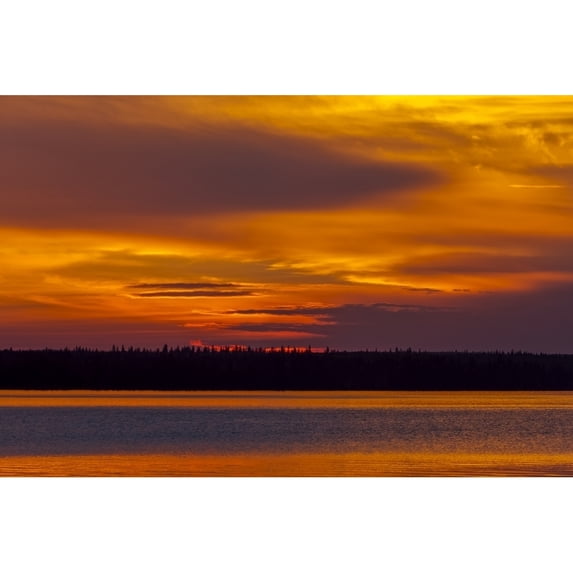 Dramatic glowing skies at sunset over a lake and silhouetted shoreline; Saskatchewan Canada Poster Print by The Nature Collection