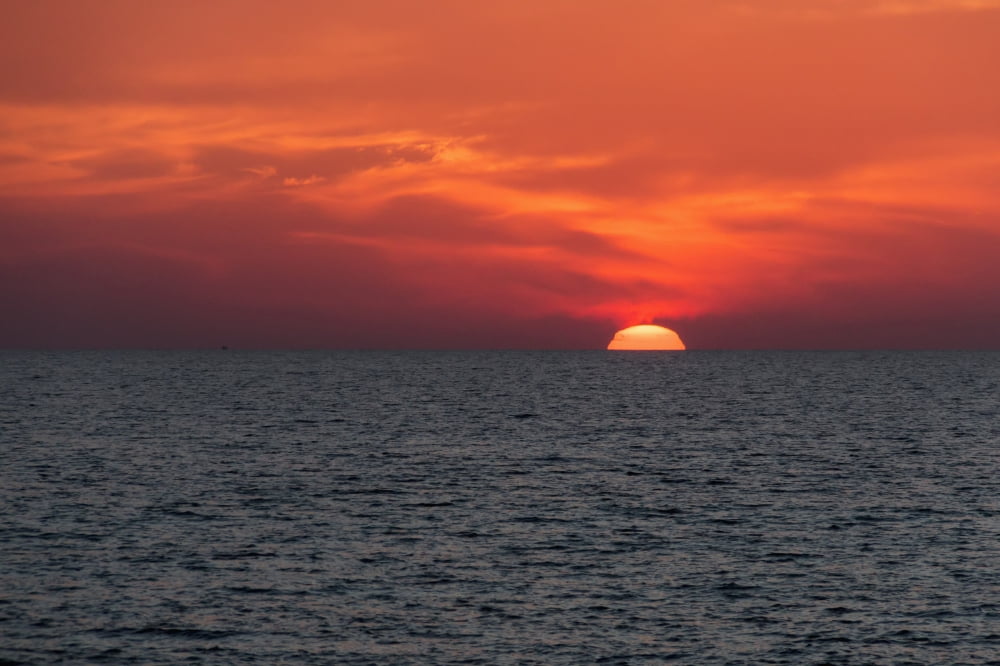 Dramatic red sky with the sun setting under the ocean and horizon Paphos Cyprus Canvas Art - John Short Design Pics (19 x 12)
