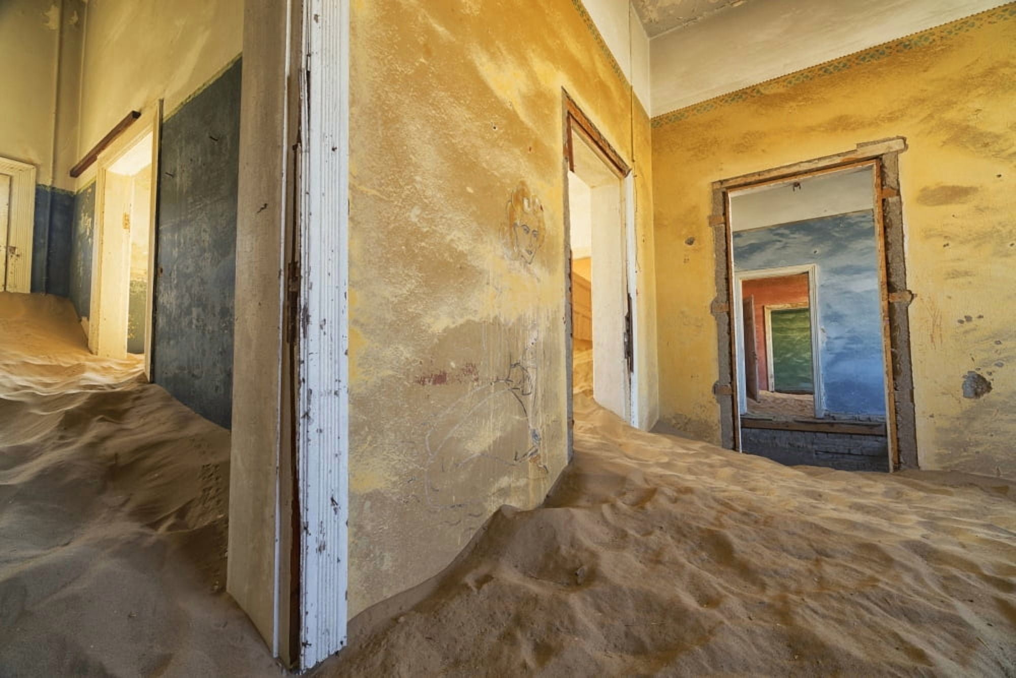 Drifting sand fills the rooms of a colourful abandoned house Kolmanskop Namibia Canvas Art - Robert Postma Design Pics (19 x 12)