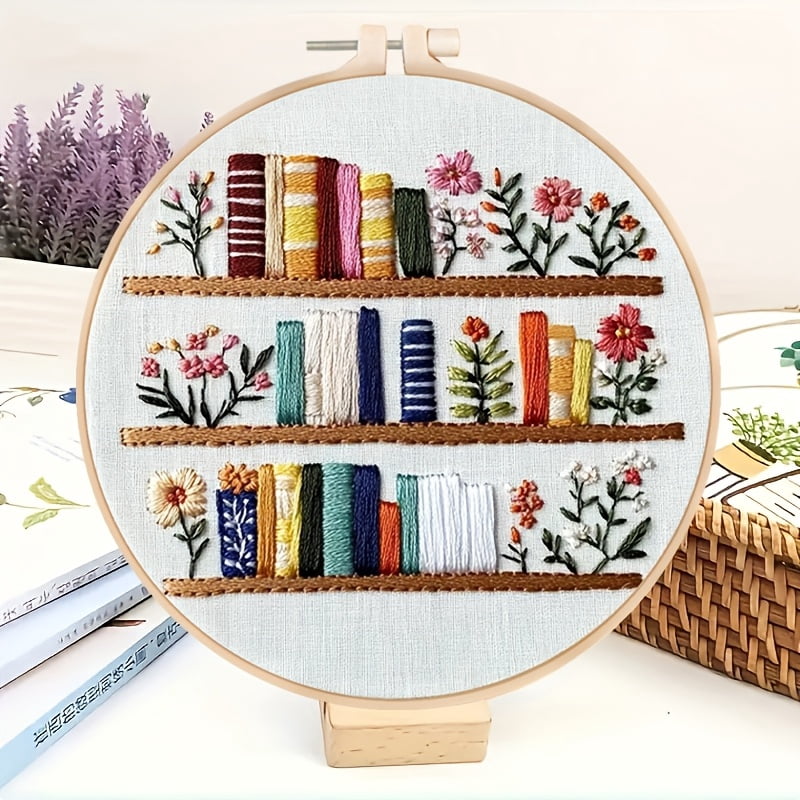 An Embroidery Kit Featuring a Bookshelf Floral Pattern Measuring, Suitable for Both Adults And Beginners. It Includes Instructions, Printed Fabric, an Embroidery Hoop, And Needle And Thread