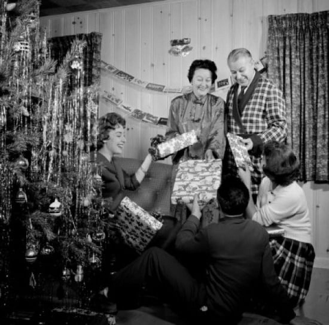 Family exchanging gifts by Christmas tree in living room Canvas Art - (24 x 36)