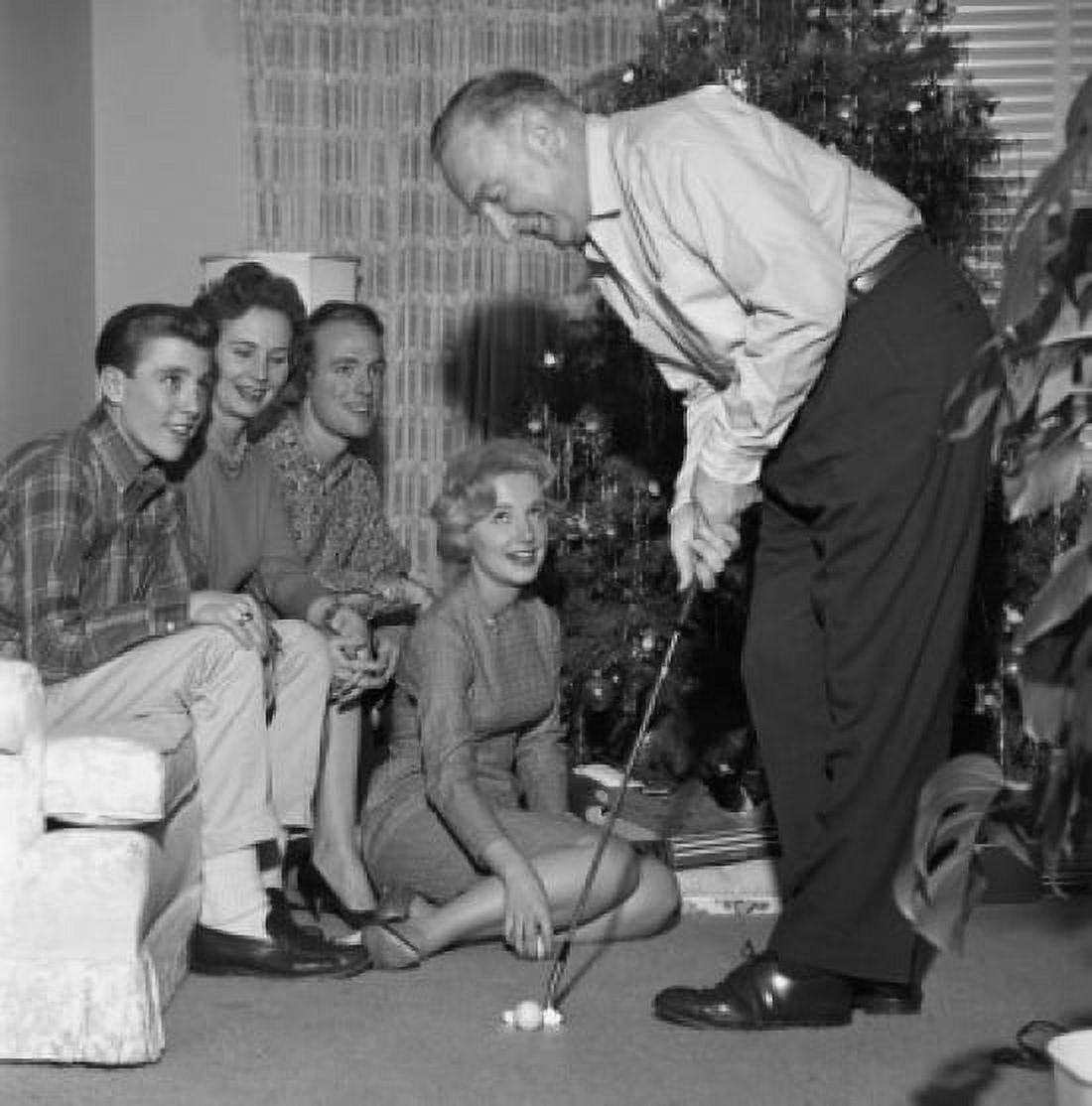 Family near Christmas tree watching man playing mini golf Canvas Art -  (18 x 24)