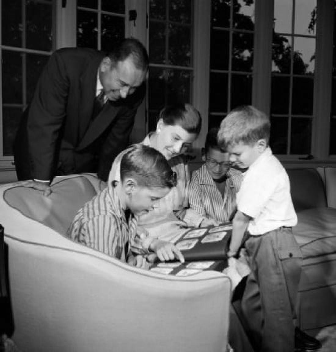 Family with three boys viewing photograph album in living room Canvas Art - (24 x 36)