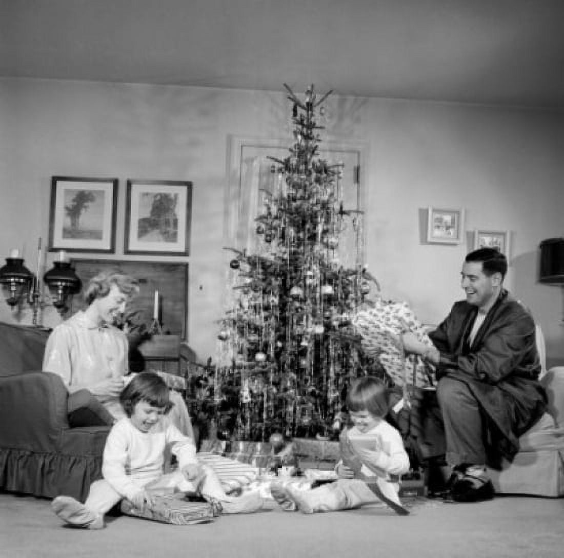 Family with two children opening gifts by Christmas tree Canvas Art - (18 x 24)