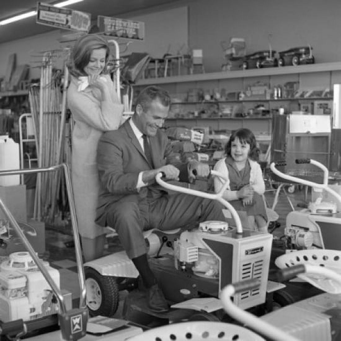 Father testing mechanical lawn mower while mother and daughter are watching Canvas Art - (24 x 36)
