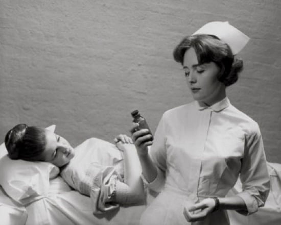 Female nurse holding a pill bottle and a patient on the bed behind her Canvas Art - (18 x 24)