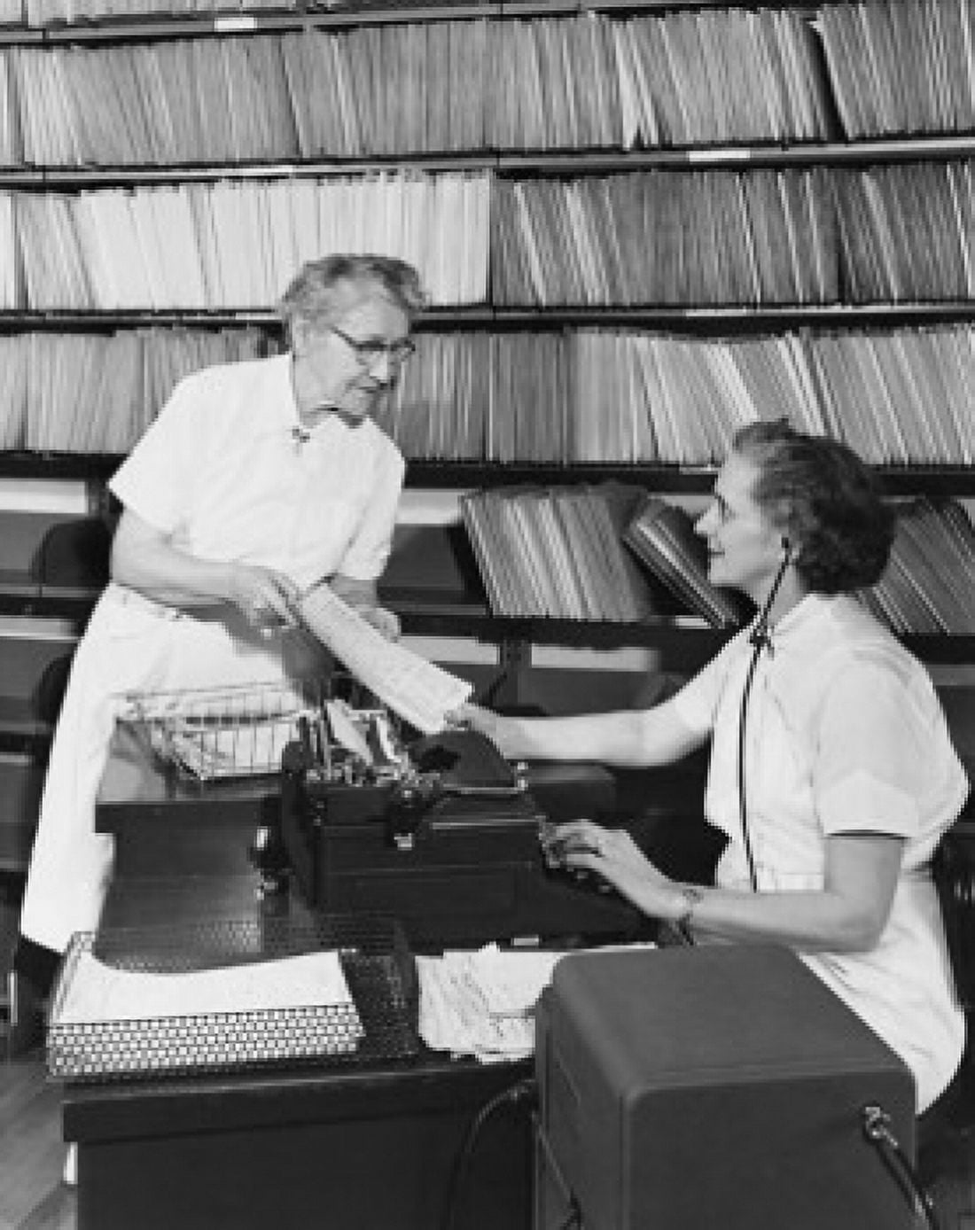 Female nurse showing a medical record to a typist in a hospital Canvas Art - (18 x 24)