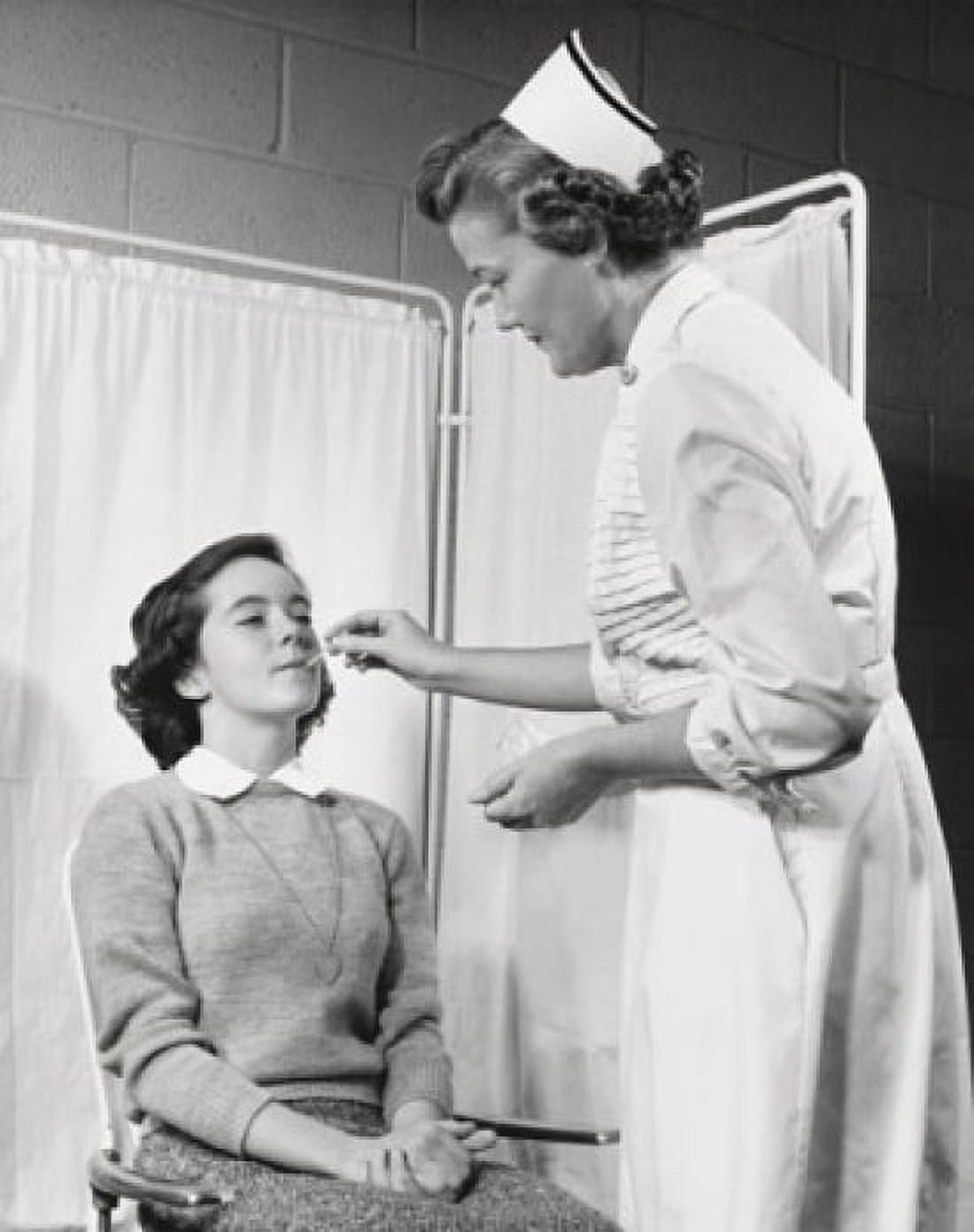 Female nurse taking the temperature of a girl with a thermometer Canvas Art - (18 x 24)