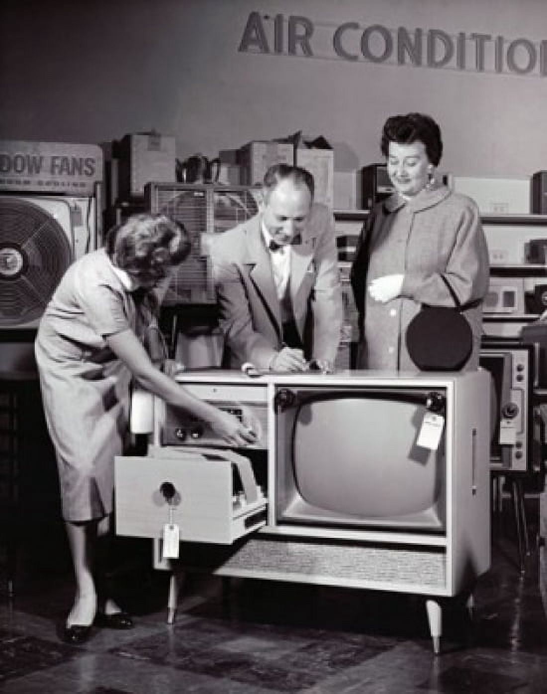 Female sales clerk showing a television set to a customer in an electronic shop Canvas Art - (24 x 36)