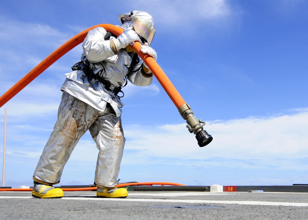 Firefighter carries a charged hose across the flight deck of USS Denver Canvas Art - Stocktrek Images (34 x 24)