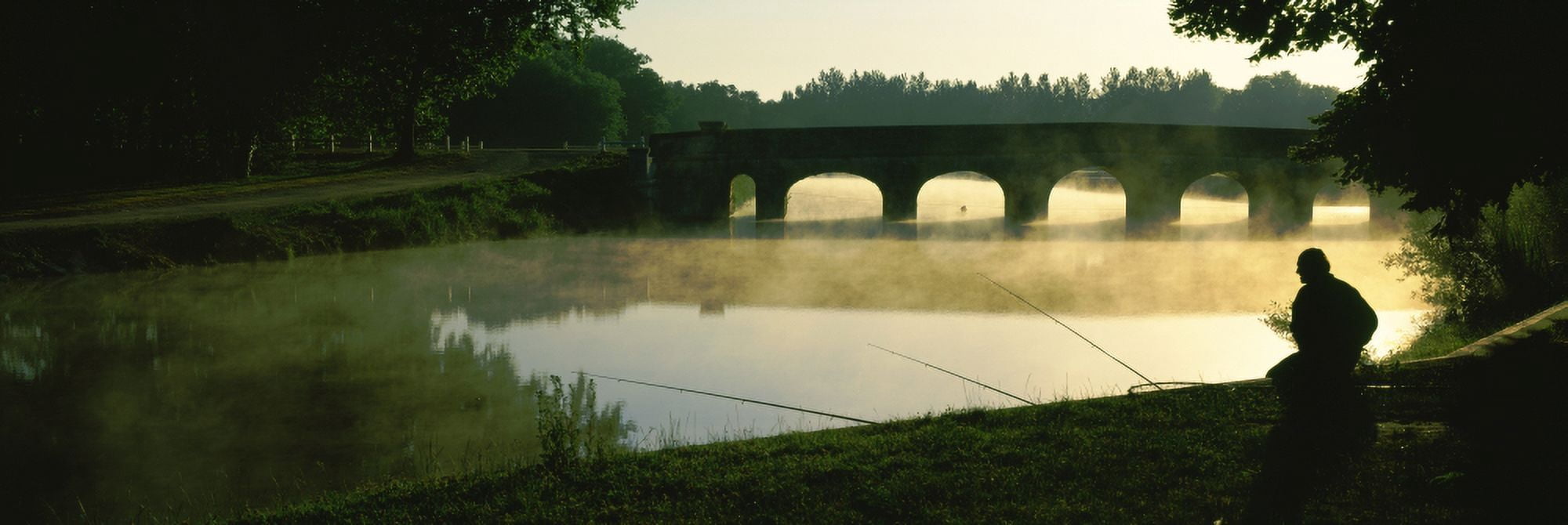 Fisherman fishing in a river with a stone bridge in the background Loire River Loire Valley France Canvas Art - Panoramic Images (27 x 9)