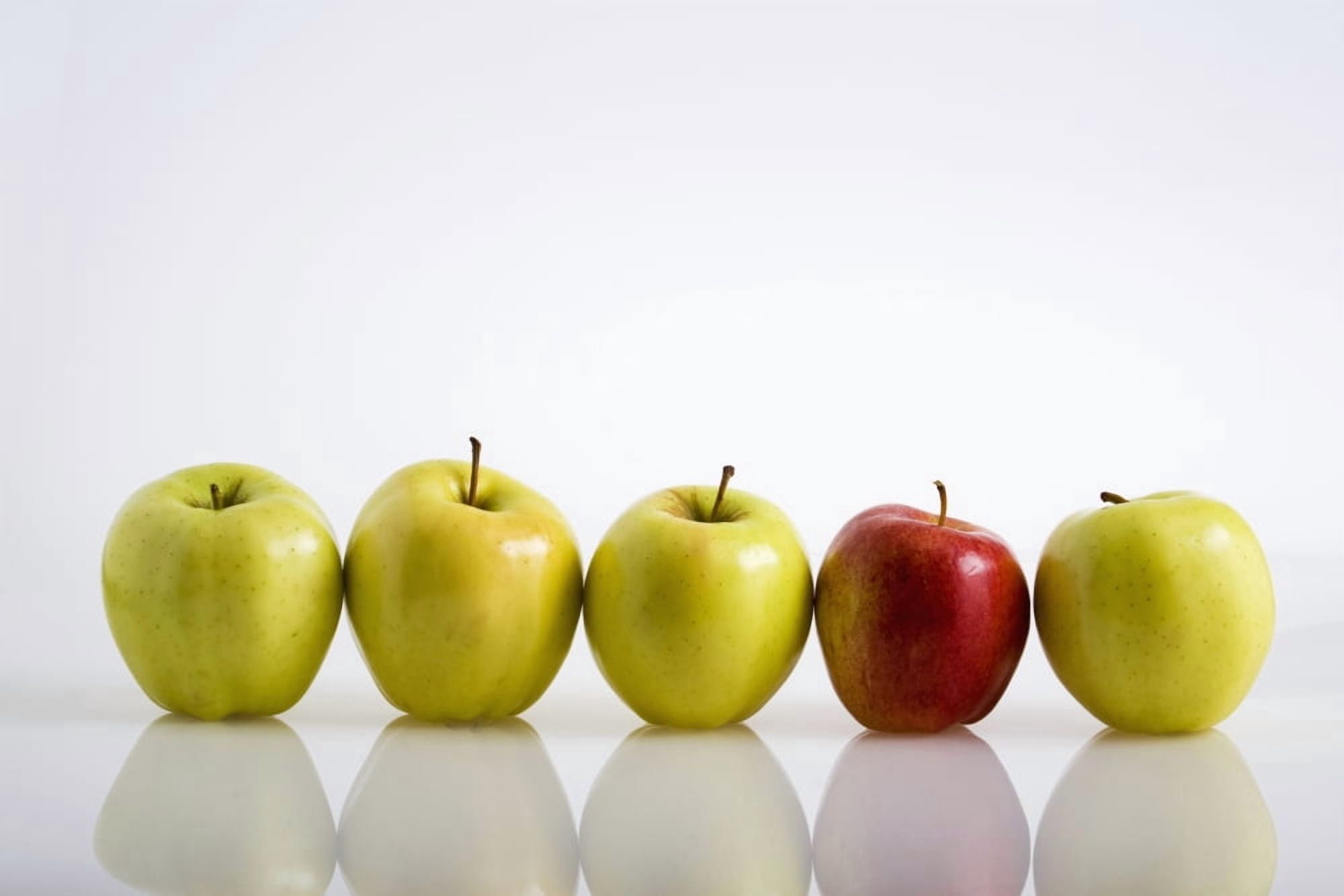Four Yellow Apples With One Red Apple In A Row On A Reflective Surface Calgary Alberta Canada Canvas Art - Michael Interisano Design Pics (19 x 12)