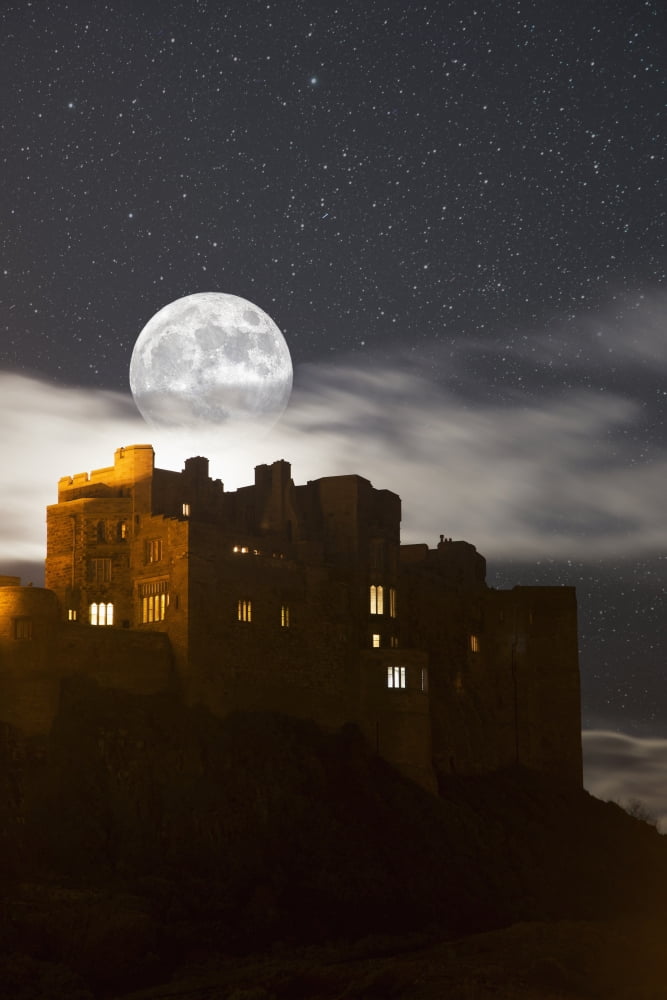 Full moon glowing in a starry sky over illuminated buildings Bamburgh Northumberland England Canvas Art - John Short Design Pics (12 x 19)