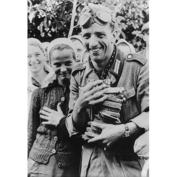 German Soldier Holding An Armful Of Sliced Bread With Several Young Ukrainian Women. German Propaganda Photo Of Welcoming Ukrainians During Operation Barbarossa Invasion. Oct. 1941. World War 2.
