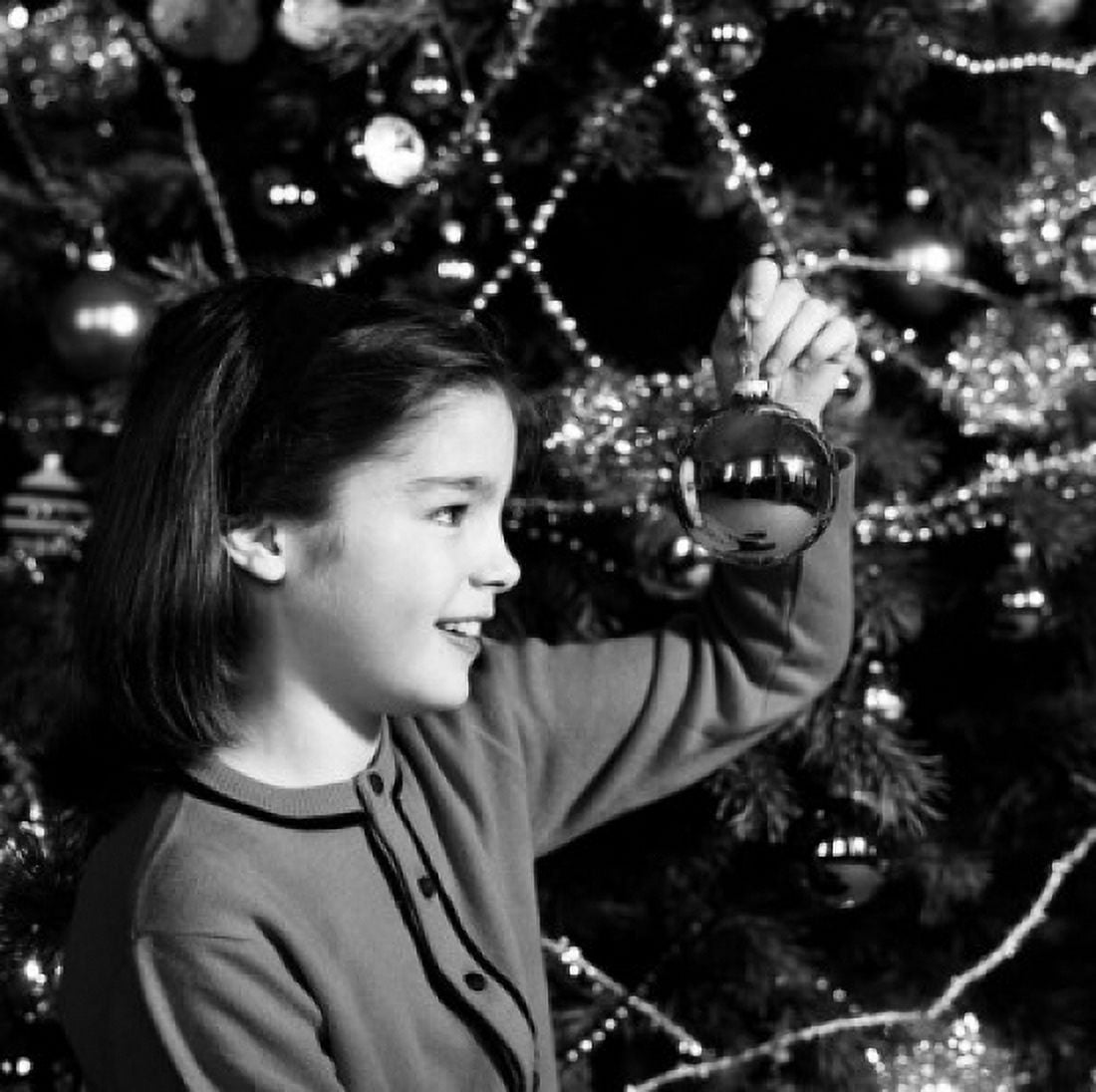 Girl holding Christmas decoration above Christmas tree Canvas Art - (24 x 36)