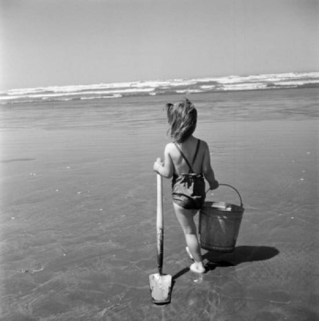 Girl holding bucket and shovel walking towards sea Canvas Art - (24 x 36)
