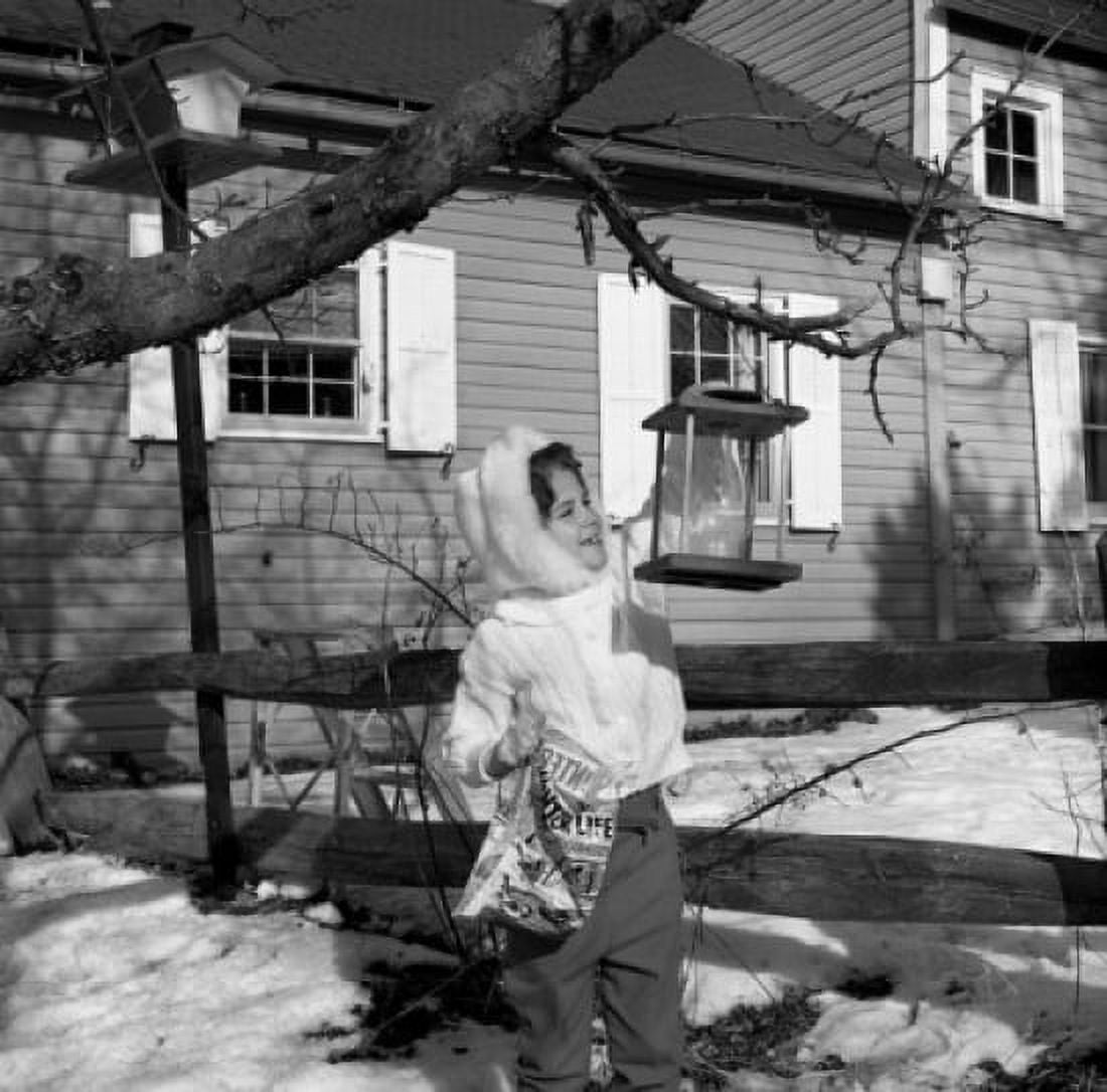 Girl putting food into birdhouse Canvas Art - (18 x 24)