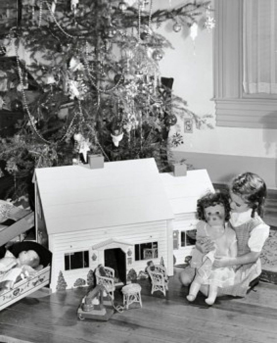 Girl sitting near a dollhouse and playing with a doll Canvas Art - (18 x 24)