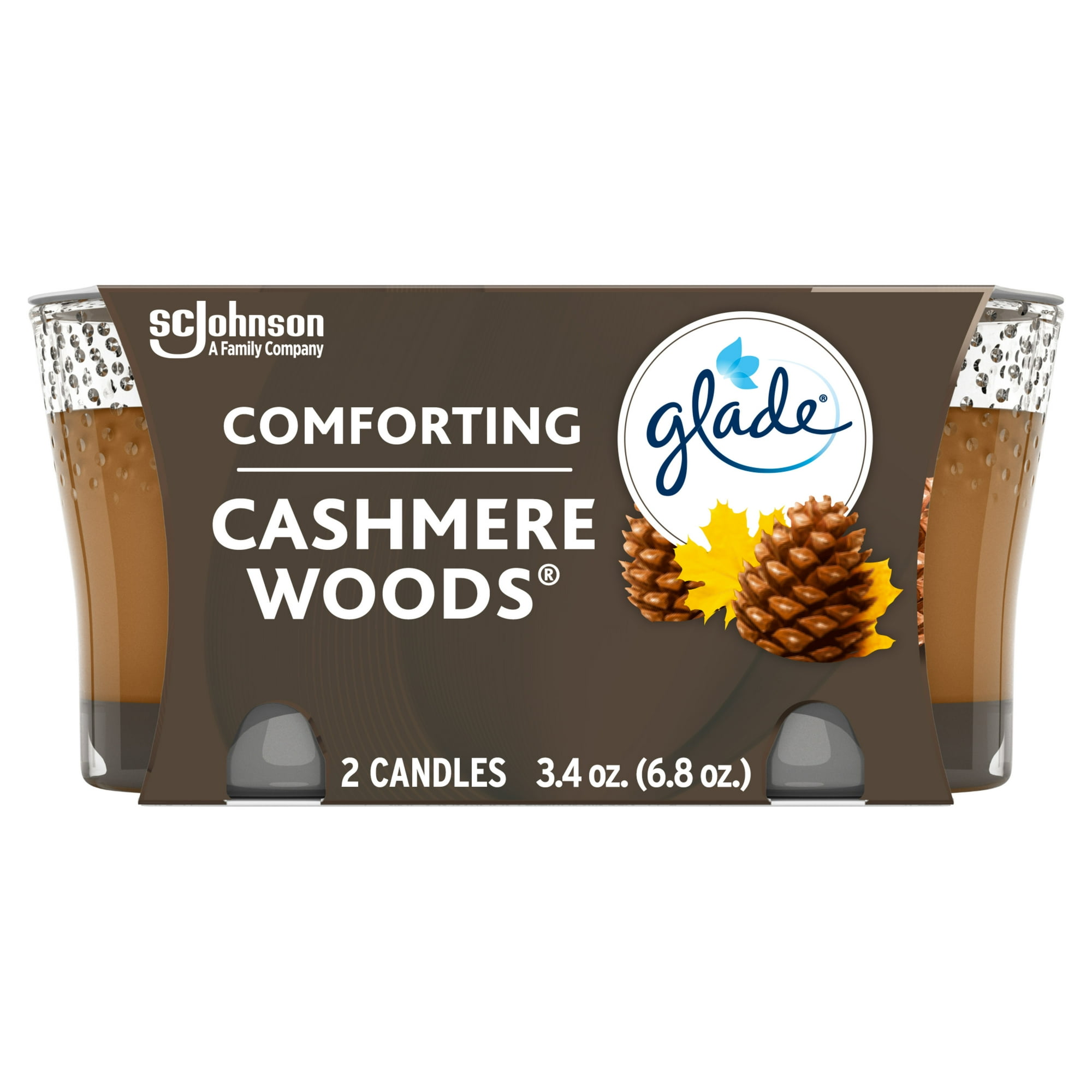 Two brown Glade Cashmere Woods candles in clear jars and white packaging that features a brown pine cone