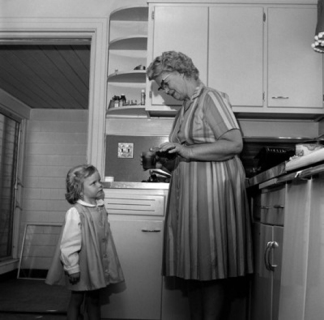 Grandmother preparing drink for granddaughter in kitchen Canvas Art - (24 x 36)