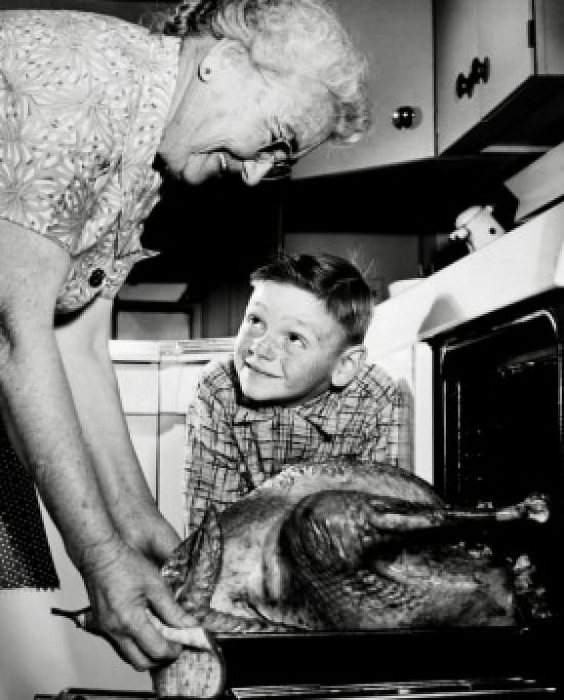 Grandmother taking a turkey from the oven with her grandson watching Canvas Art - (18 x 24)