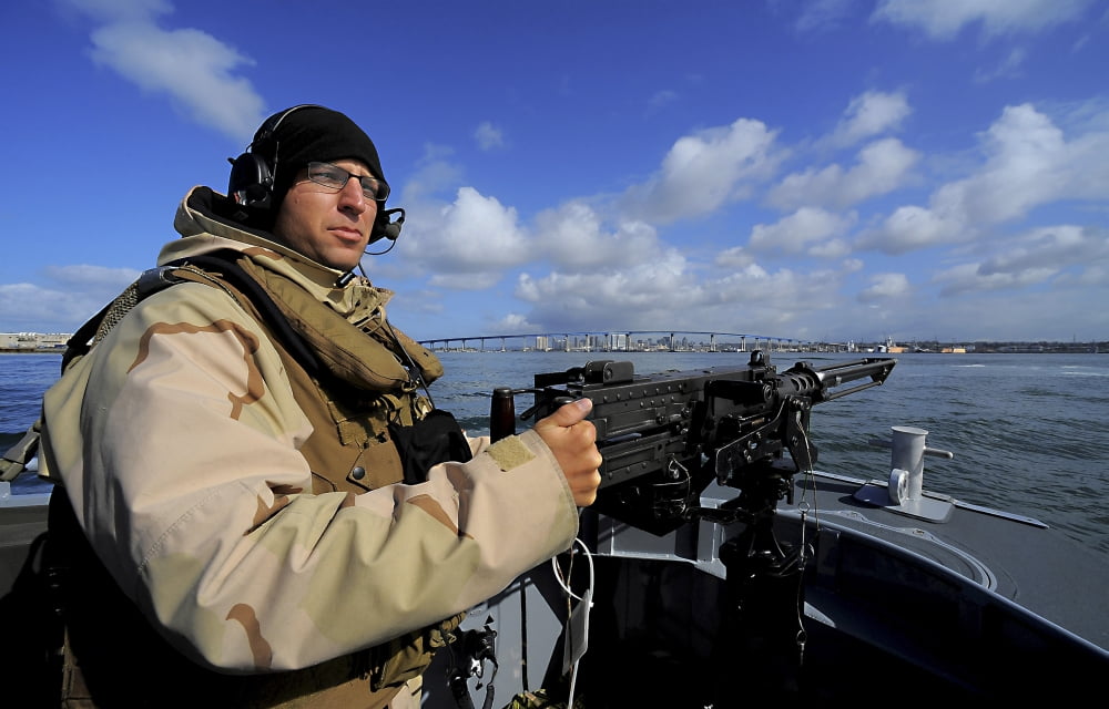 Gunners Mate mans an M2 HB 50-caliber machine gun on the forward mount of a rigid-hull inflatable boat Canvas Art - Stocktrek Images (35 x 22)