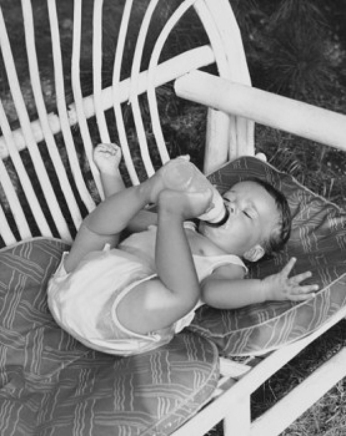 High angle view of a baby lying on a couch and drinking milk from a bottle Canvas Art - (18 x 24)
