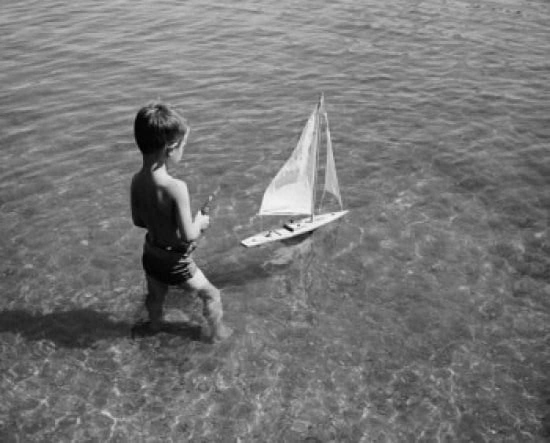 High angle view of a boy playing with a toy boat in water Canvas Art - (24 x 36)