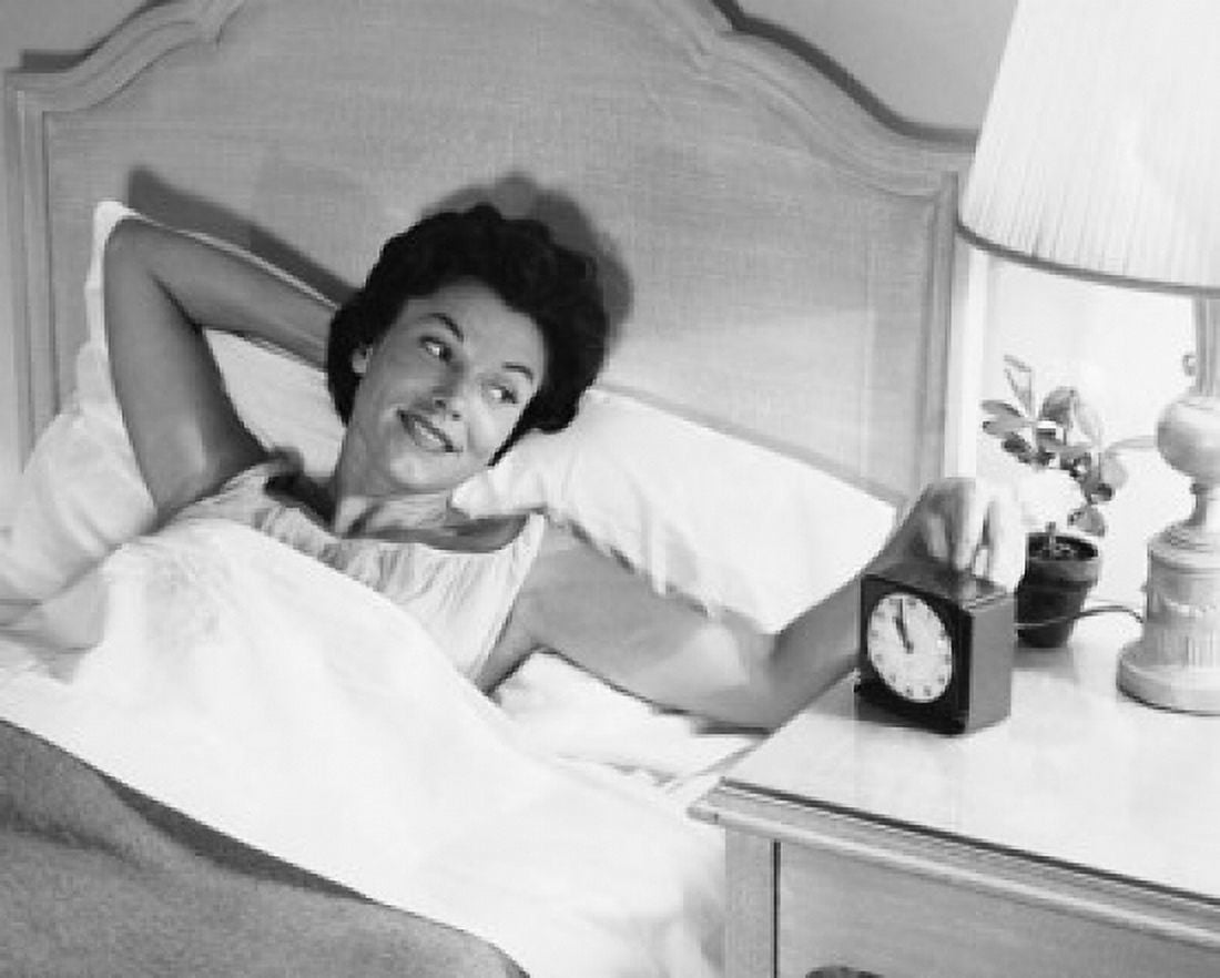 High angle view of a young woman lying in the bed and turning on an alarm clock Canvas Art - (18 x 24)