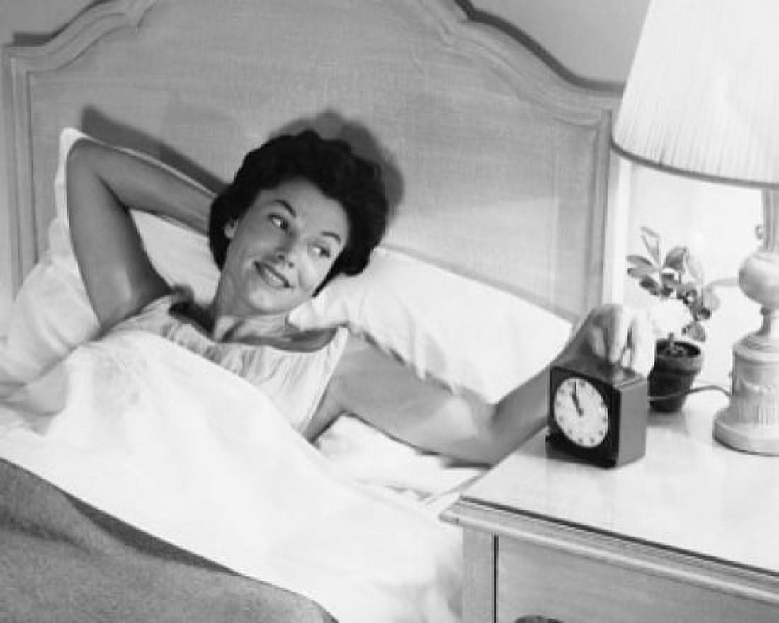 High angle view of a young woman lying in the bed and turning on an alarm clock Canvas Art - (24 x 36)