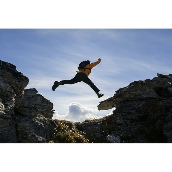 Hiker Leaps Between Rocks Near Noatak River In The Brooks Range Gates Of The