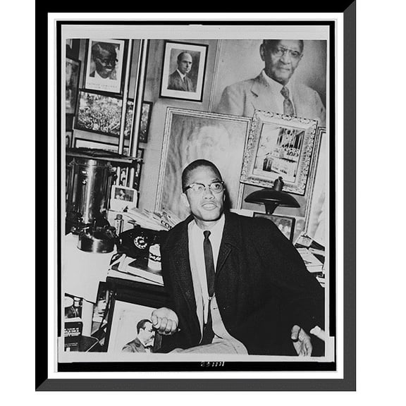Historic Framed Print, [Malcolm X, half-length portrait, seated, facing right, during press conference in offices of the National Memorial African Book Store, New York City], 17-7/8" x 21-7/8"