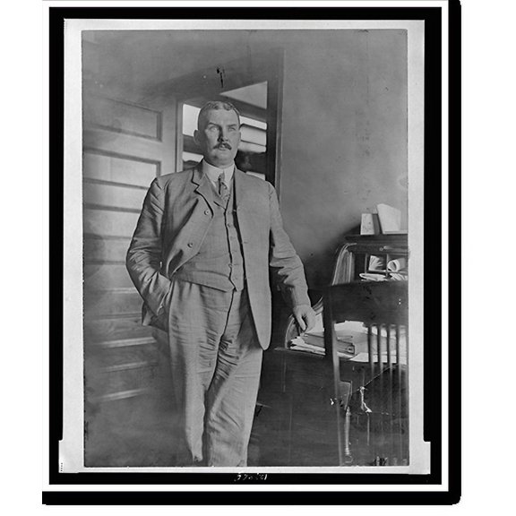 Historic Print, [John Ford, three-quarter length portrait, standing, facing slightly right, with his left hand on rolltop desk], 18" x 24"