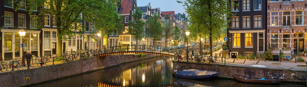 Houses along canal at dusk at intersection of Herengracht and Brouwersgracht Amsterdam North Holland Netherlands Canvas Art - Panoramic Images (27 x 9)