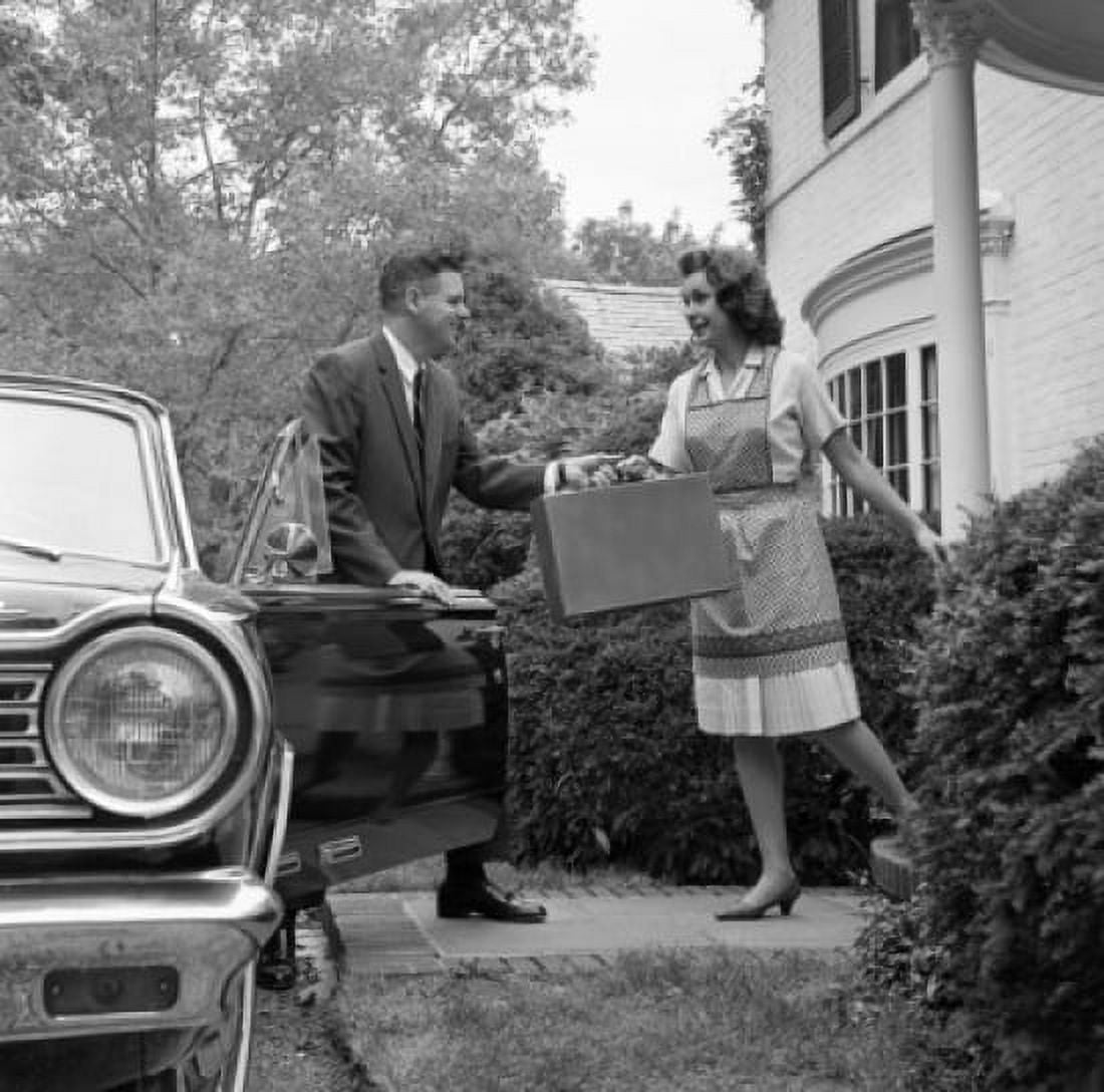 Housewife passing suitcase to husband in front of house Canvas Art - (24 x 36)