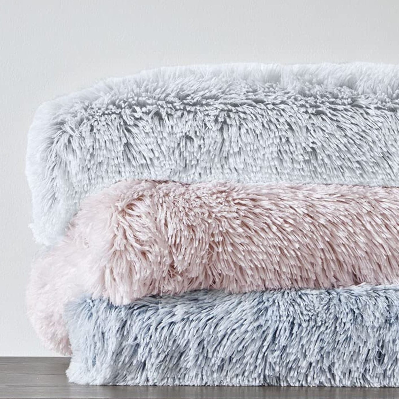 3 faux fur blankets stacked in a pile