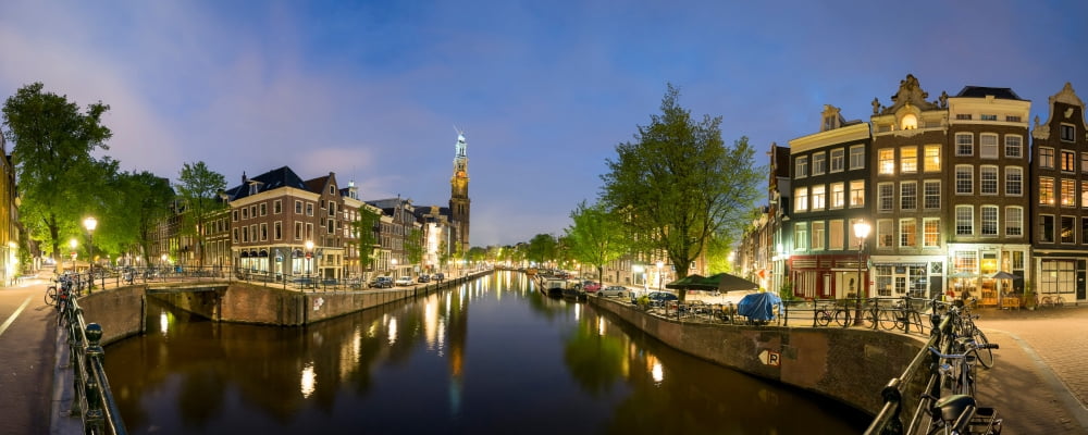 Intersection of Prinsengracht and Leidsegracht canals at night with tower of Westerkerk church in distance Amsterdam North Holland Netherlands Canvas Art - Panoramic Images (27 x 9)