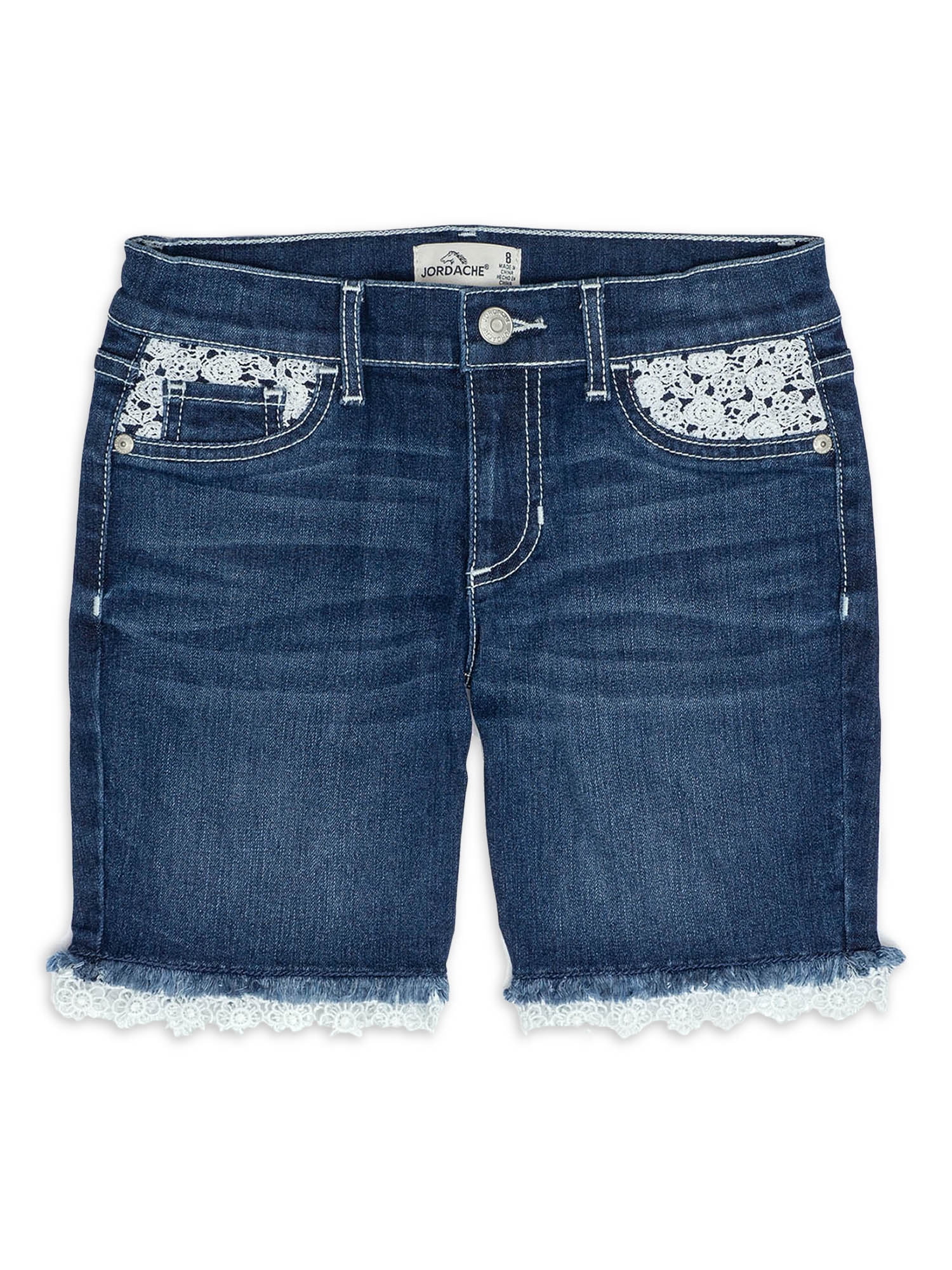 A girl wearing a white shirt and blue denim shorts and standing on a