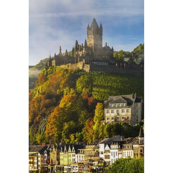 Large medieval castle on top of a colourful treed hillside with fog, blue sky, cloud and village below; Cochem, Germany by Michael Interisano / Design Pics (24 x 38)