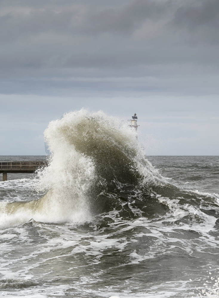 Large wave crashing at the coast with a lighthouse at the end of a pier Amble Northumberland England Canvas Art - John Short Design Pics (26 x 36)
