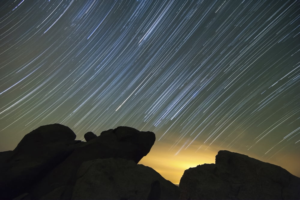 Light pollution illuminates the sky and star tails above large boulders Canvas Art - Dan BarrStocktrek Images (18 x 12)