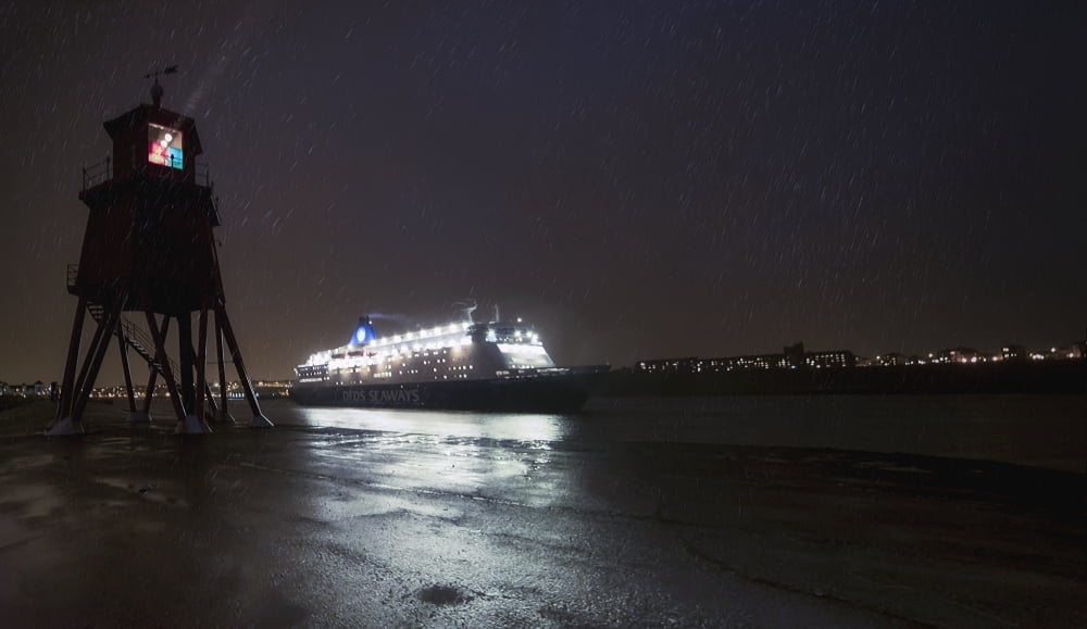 Light streaming from a lighthouse on the coast as an illuminated cruise ship passes by South Shields Tyne and Wear England Canvas Art - John Short Design Pics (38 x 22)