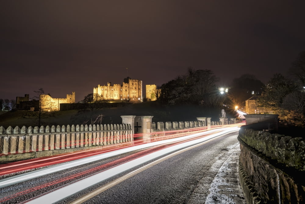 Light trails on a road and illuminated building in the background at nighttime Alnwick Northumberland England Canvas Art - John Short Design Pics (19 x 12)