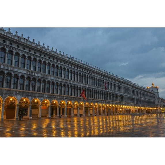 Lighted archways in a row along a building reflected in the wet pavement Piazza san marco; Venice Veneto Italy