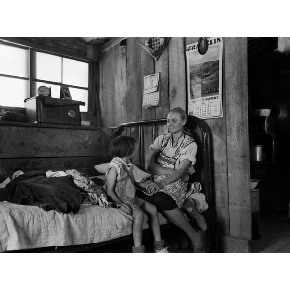 Listening To The Radio. A Mother Smiles At Her Daughter As They Listen To The Radio In Their Dugout Home. It Was One Of